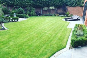  Level lawn in a residential garden with architectural planting and stone water