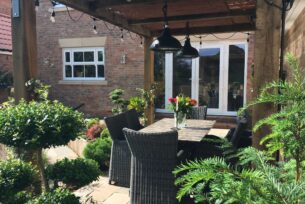  Outdoor sofa area with oak pergola and natural planting.