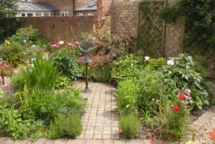  Naturalistic planting design with stone sett path leading to a statue.