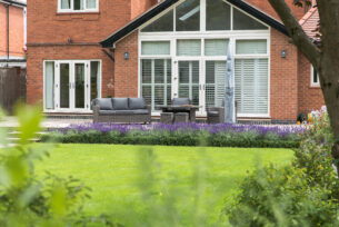  View over a new lawn to lavender planting and a raised patio using natural stone paving.