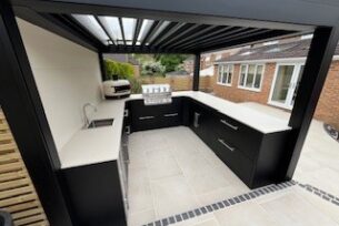  Bespoke metal outdoor kitchen with a metal pergola overhead. Porcelain paving.