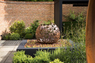  Circular steel water feature in a raised bed surrounded by planting.