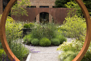  Central steel sculpture using horseshoes surrounded by lavender and verbena planting with a walled background.