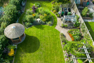  Crescent shaped lawn with mature planting to surround and a breeze house to the corner.