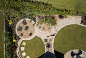  Aerial view of a circular lawn with stone walling and planting.