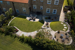  Aerial view of a split level garden showing lawn, stone waling in a curve and planting.