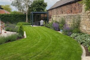  Modern garden design using porcelain paving and lavender planting with a natural lawn and metal pergola.