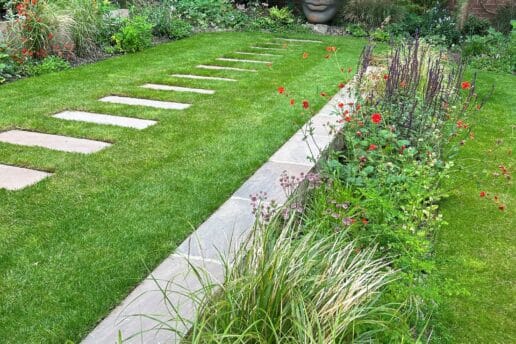An urban garden in Harrogate with retaining wall, level lawn and garden artwork as a focal point